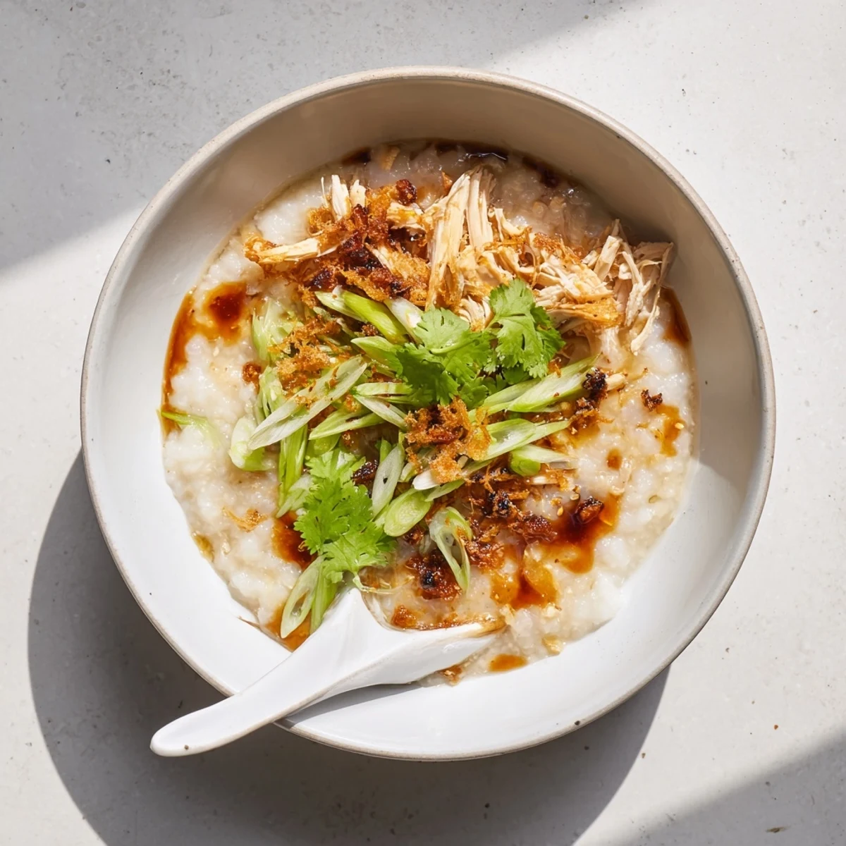 Comforting chicken congee with shredded tender chicken floating in a rich, creamy rice broth