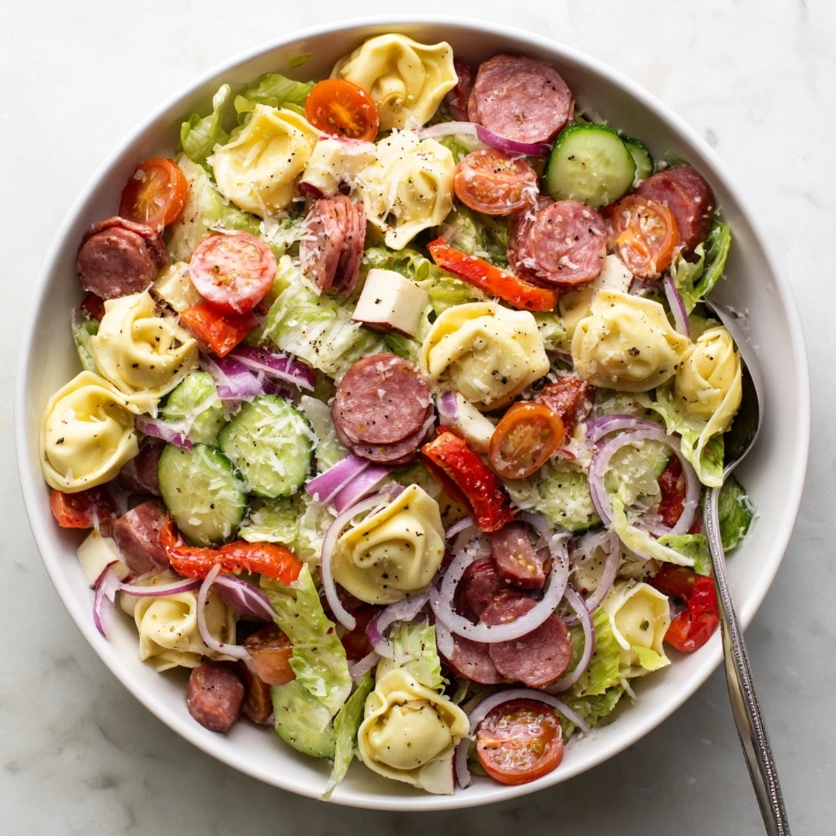 Colorful bowl of fresh grinder tortellini salad with cherry tomatoes, provolone, and crisp vegetables tossed in zesty Italian dressing