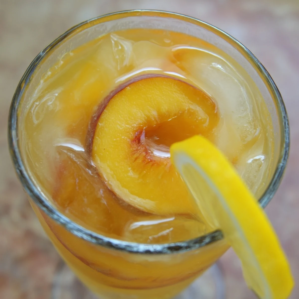 Refreshing peach lemonade drink with ice cubes and fresh mint sprigs on wooden table