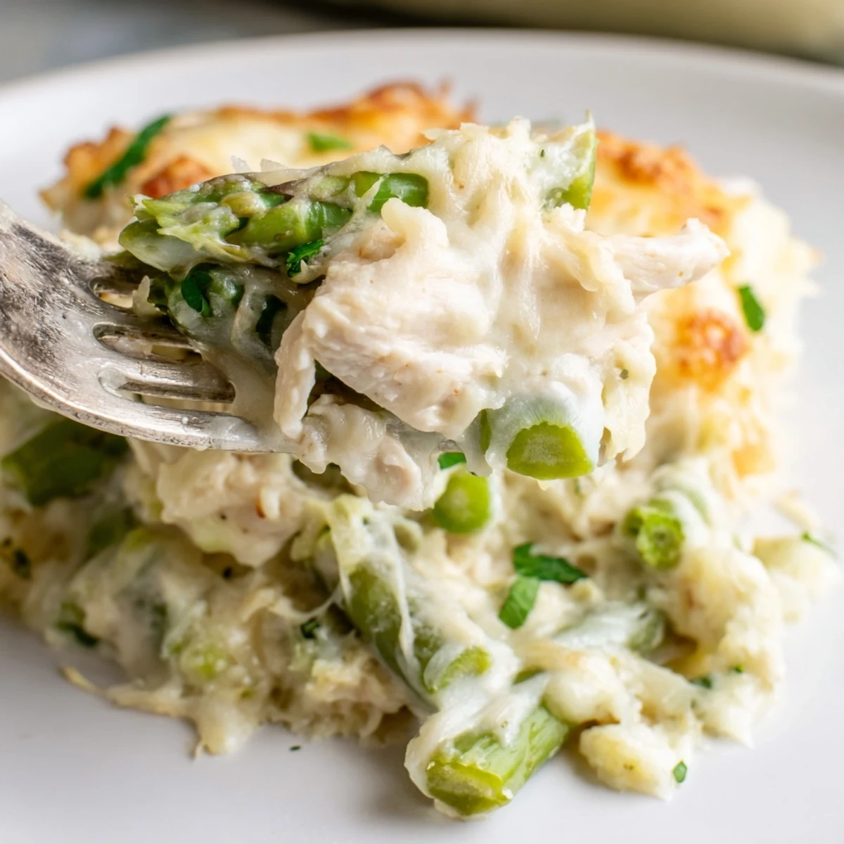 Creamy Chicken Asparagus Bake pictured in a baking dish, golden cheese and parsley garnish