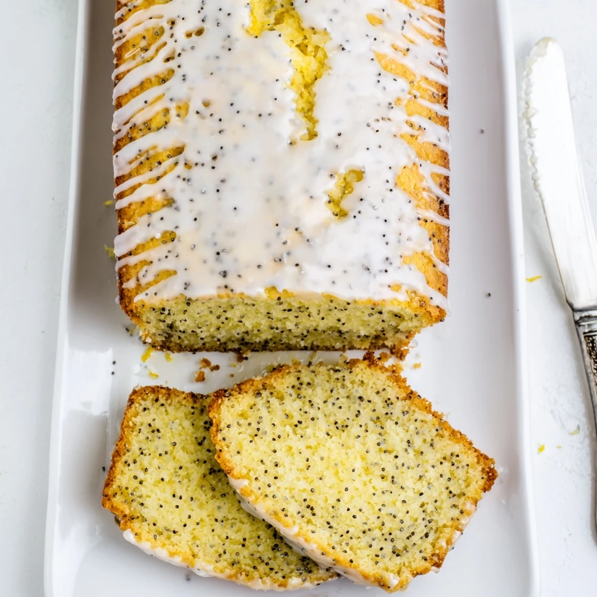 Golden zesty lemon poppy seed loaf drizzled with white glaze on wooden board