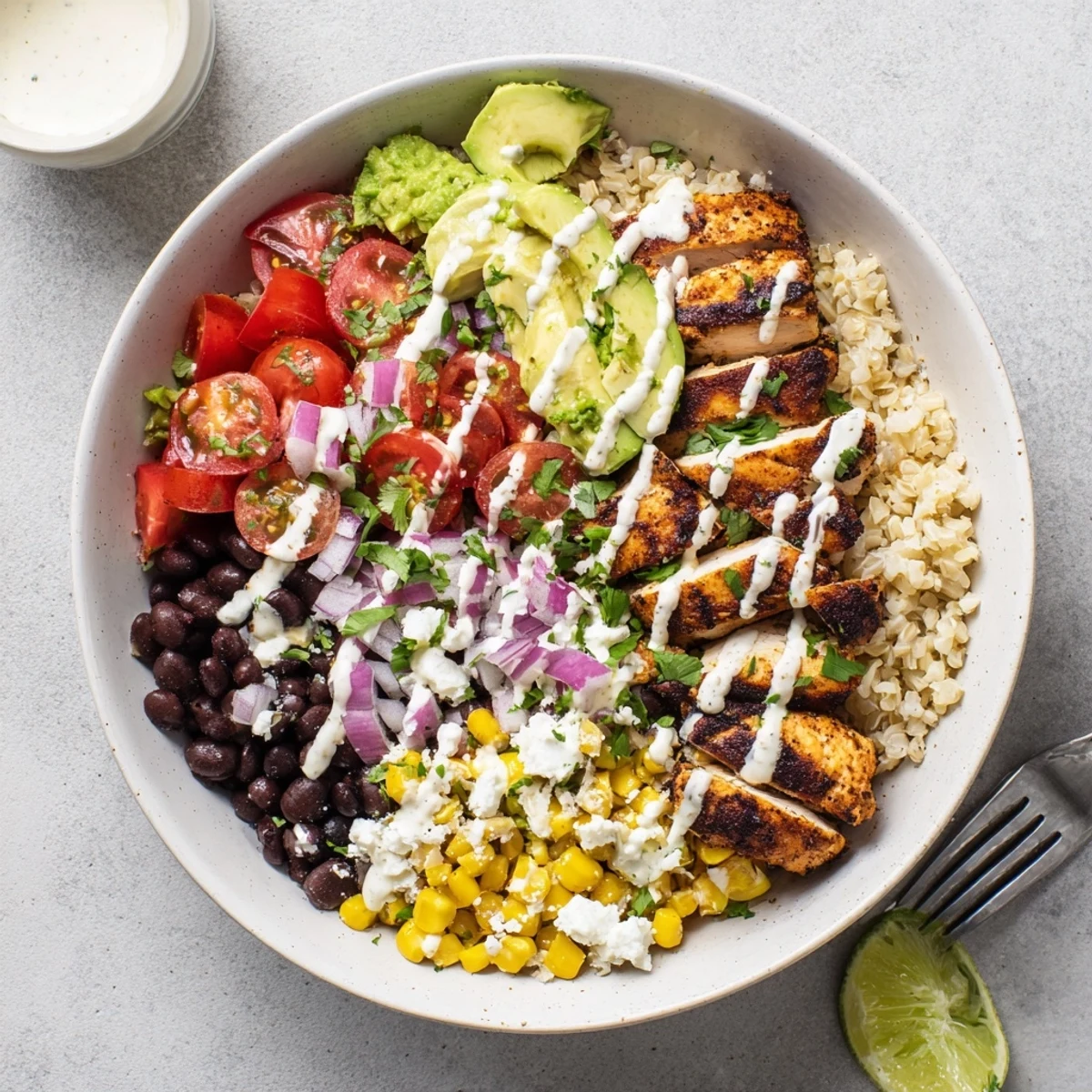 Hearty Mexican Chicken Grain Bowl topped with fresh avocado and zesty lime crema drizzle