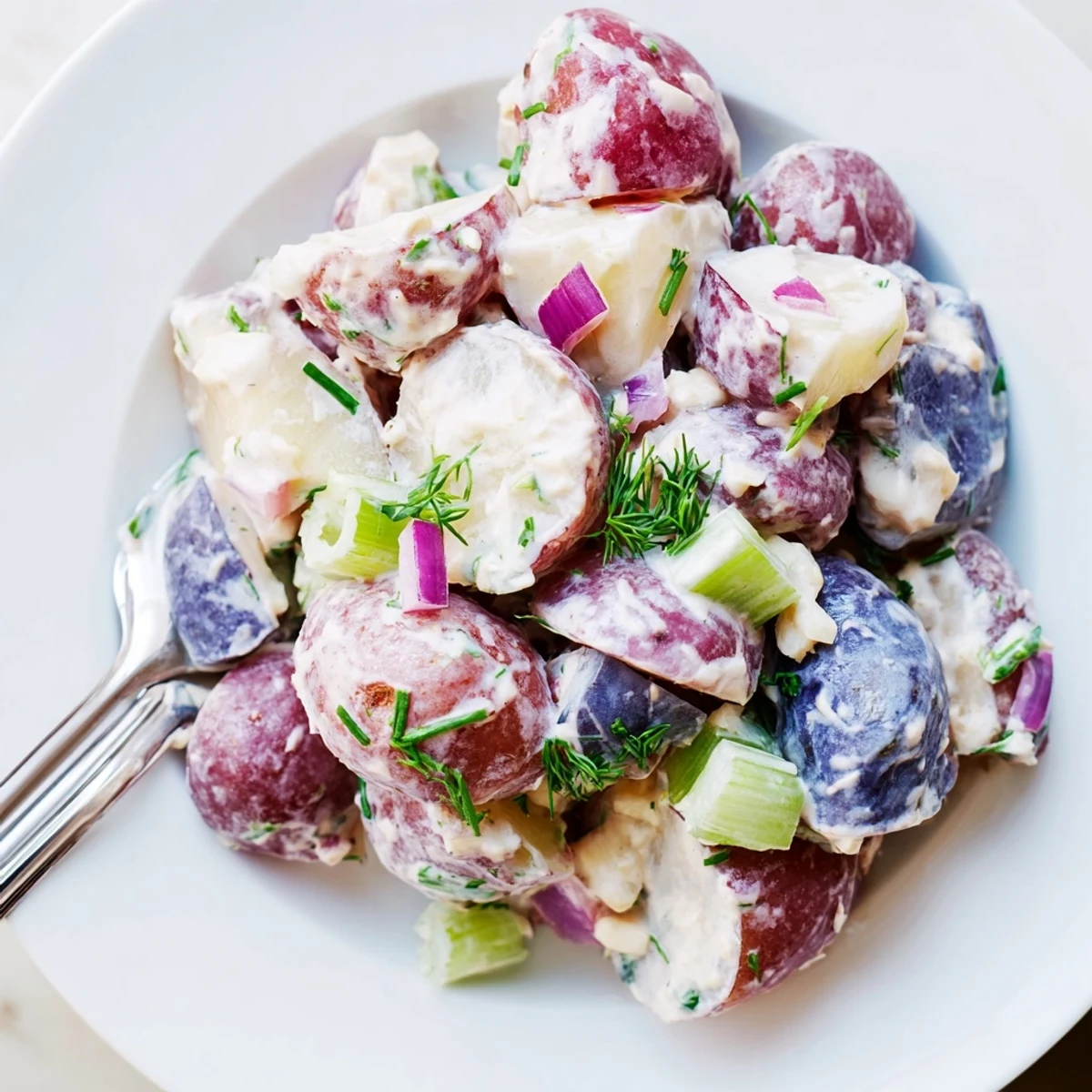 Red White Blue Potato Salad topped with fresh herbs in a rustic serving bowl