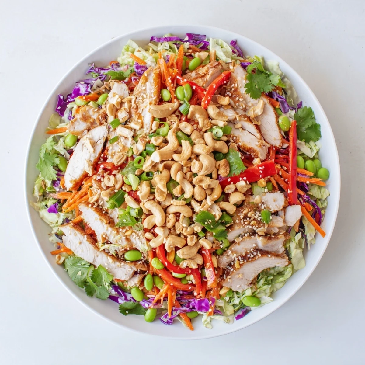 Colorful chicken cashew crunch salad topped with roasted nuts and sesame dressing