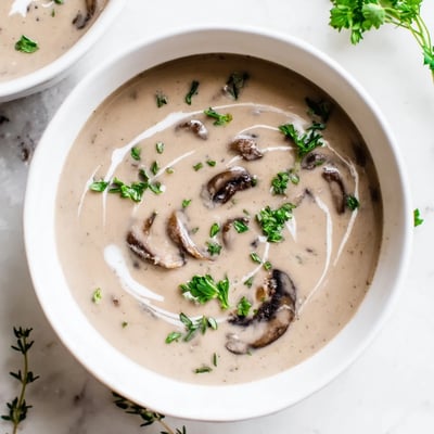 Creamy Mushroom Soup with Thyme served in a rustic ceramic bowl beside crusty artisan bread for dipping.